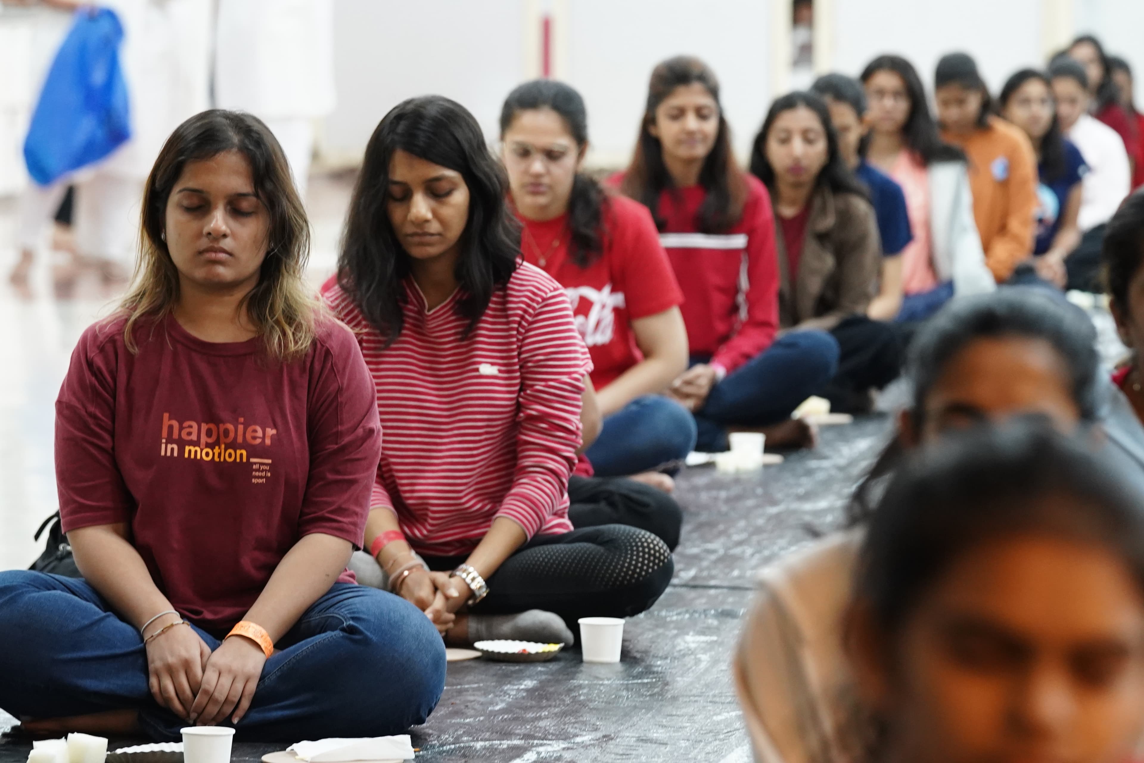 Young participants meditate together with eyes closed