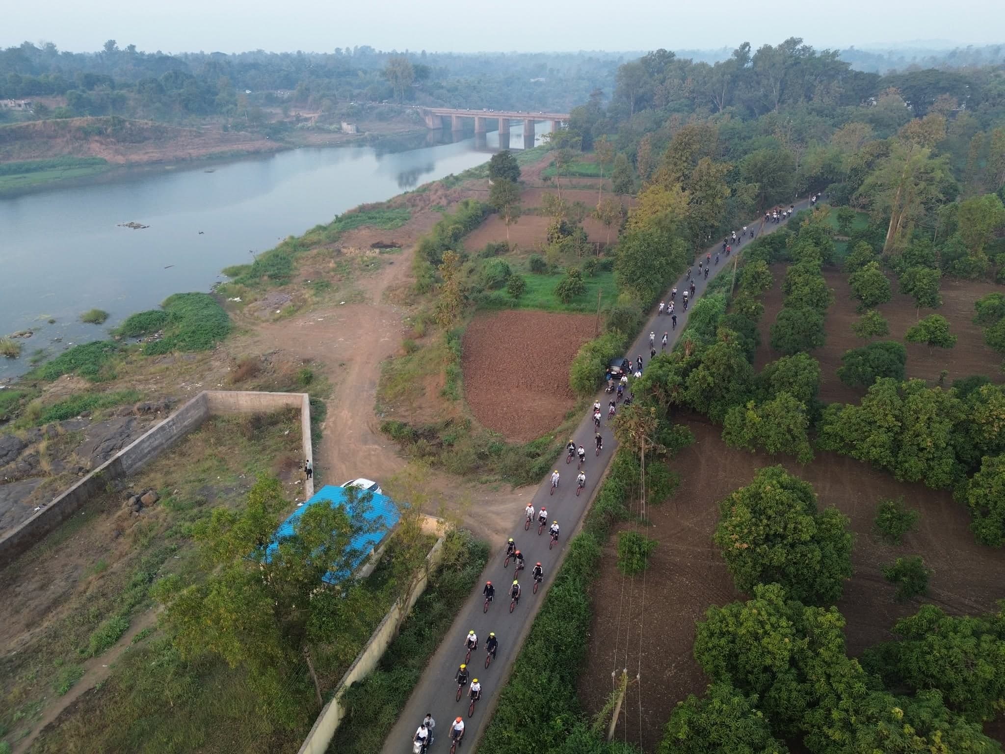 Cyclists follow a tree-lined road beside the water during the 2023 festival