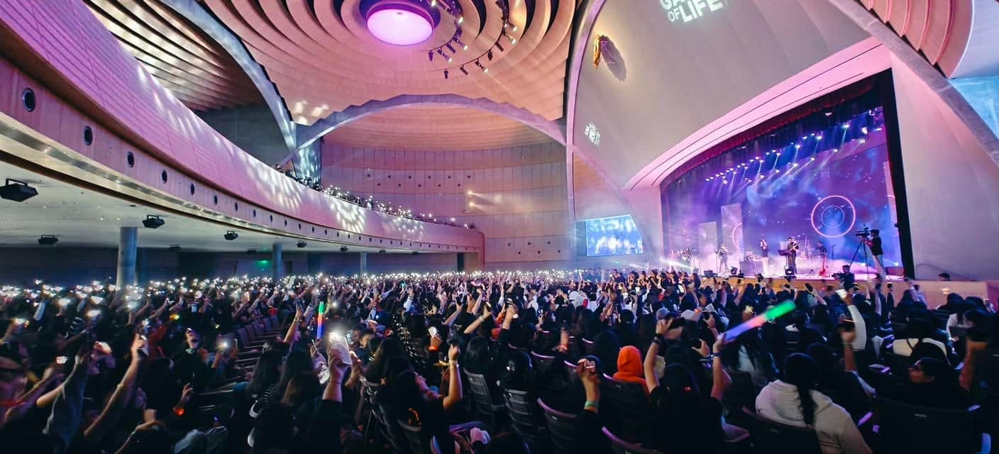 Festival participants celebrate together in the illuminated Dharampur auditorium