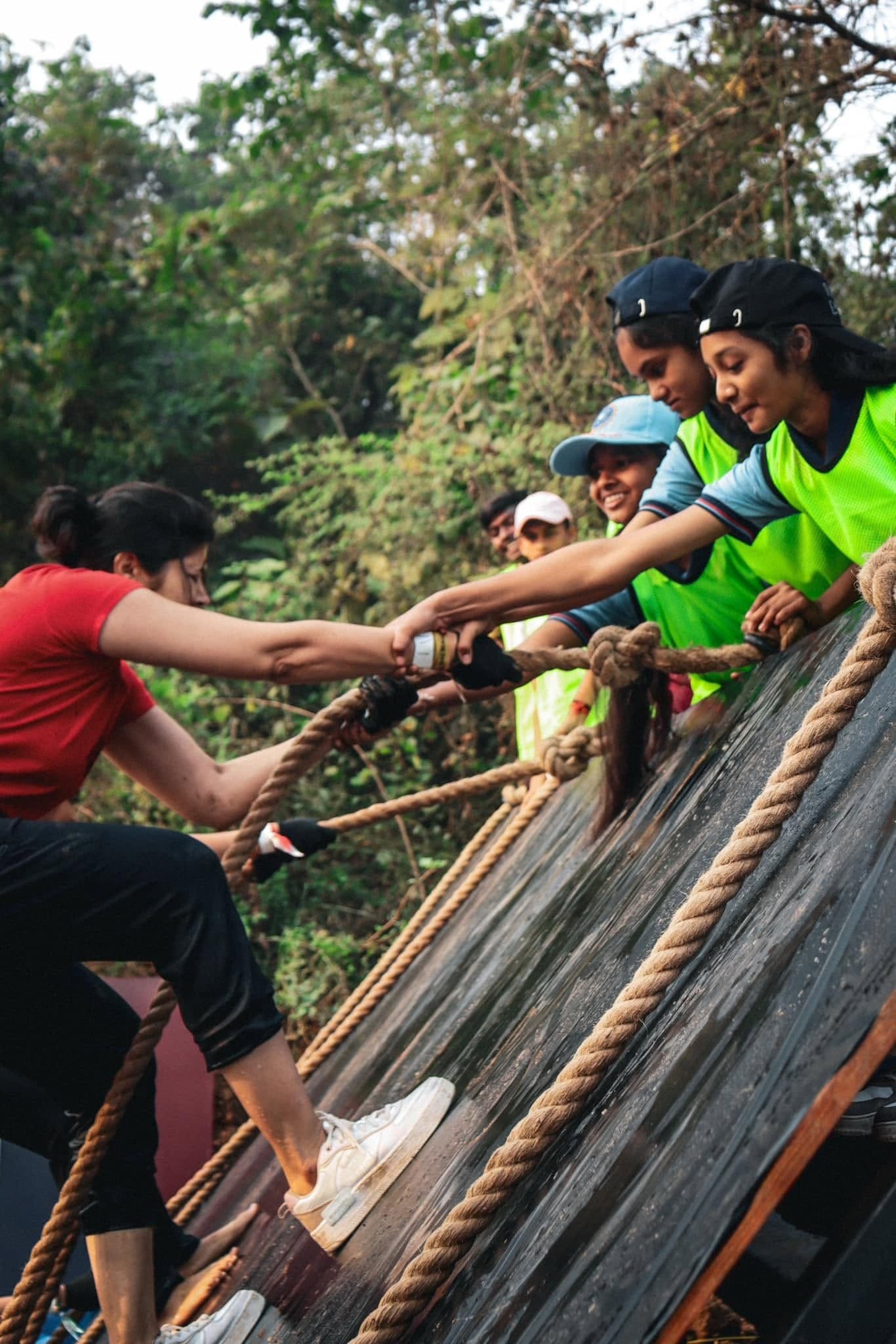 Teammates help a participant climb an obstacle at the 2024 festival